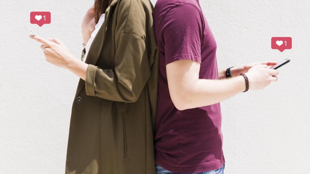 Una pareja de espalda con móviles en la mano.