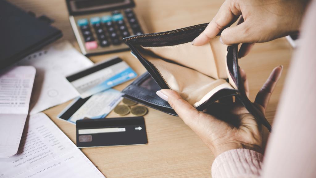 Mano de mujer abriendo un monedero vacío (iStock)