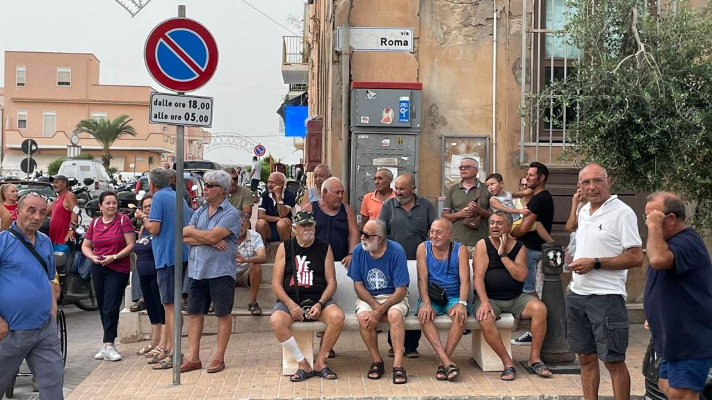 Un grupo de lampedusanos espera en la calle durante una asamblea de la comunidad para debatir el problema migratorio.