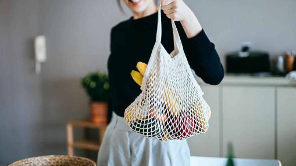 Imagen de una mujer sujetando una bolsa con verduras.