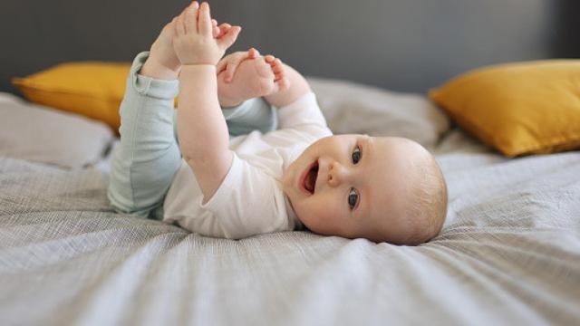 Imagen de un bebé sonriendo en la cama.