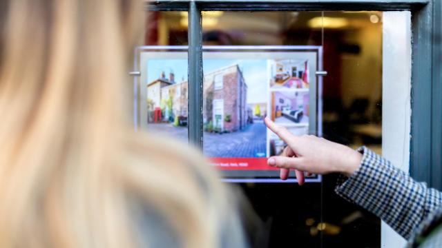 Una persona observa los anuncios de un escaparate de una inmobiliaria.