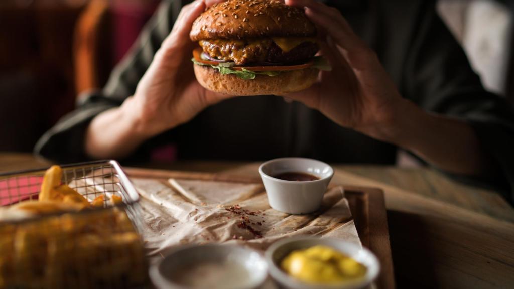 Una persona se come en casa una hamburguesa, en una imagen de archivo.