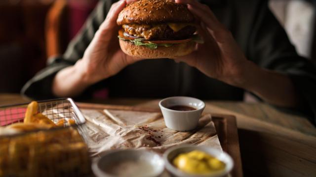 Una persona se come en casa una hamburguesa, en una imagen de archivo.