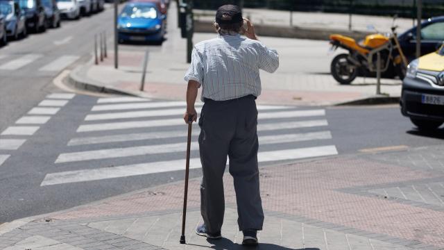 Un hombre mayor pasea apoyándose en un bastón.