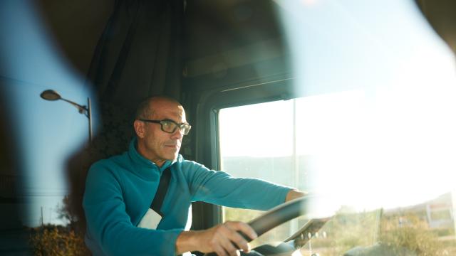 Un hombre conduce un camión por la carretera.