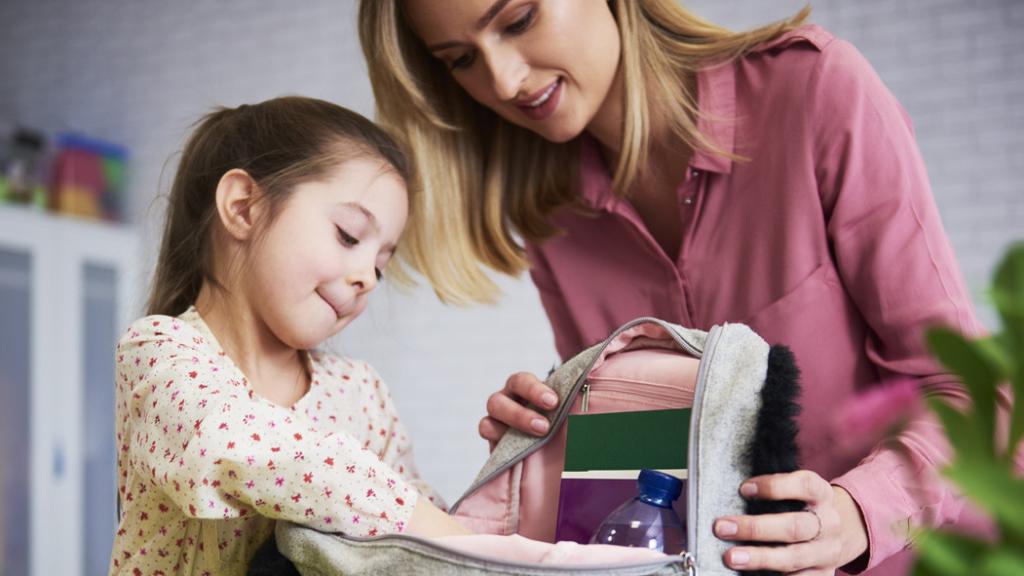 Una mujer preparando la merienda para el colegio a su hija.