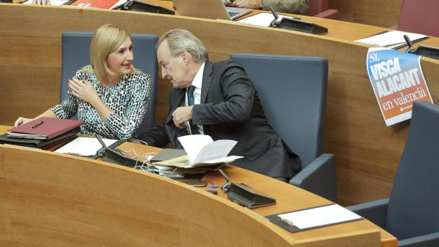 La consellera Salomé Pradas habla con el conseller José Luis Aguirre este jueves en les Corts