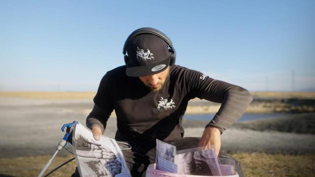 El reconocido artista de 'land-art' francés Saype hojea sus bocetos antes de ponerse a pintar.