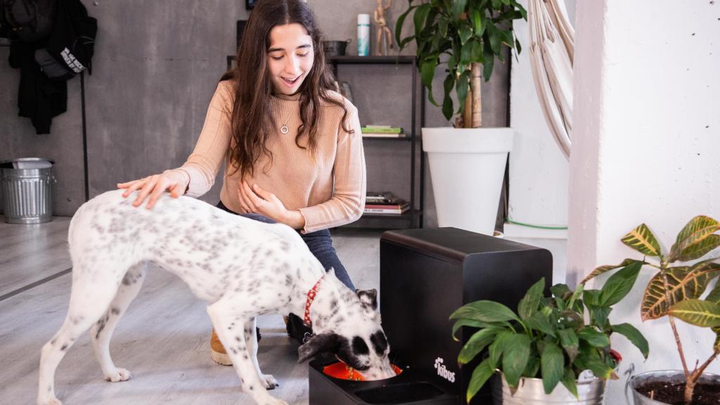 Una usuaria ofrece comida a su mascota elaborada por el robot de Kibus Petcare.
