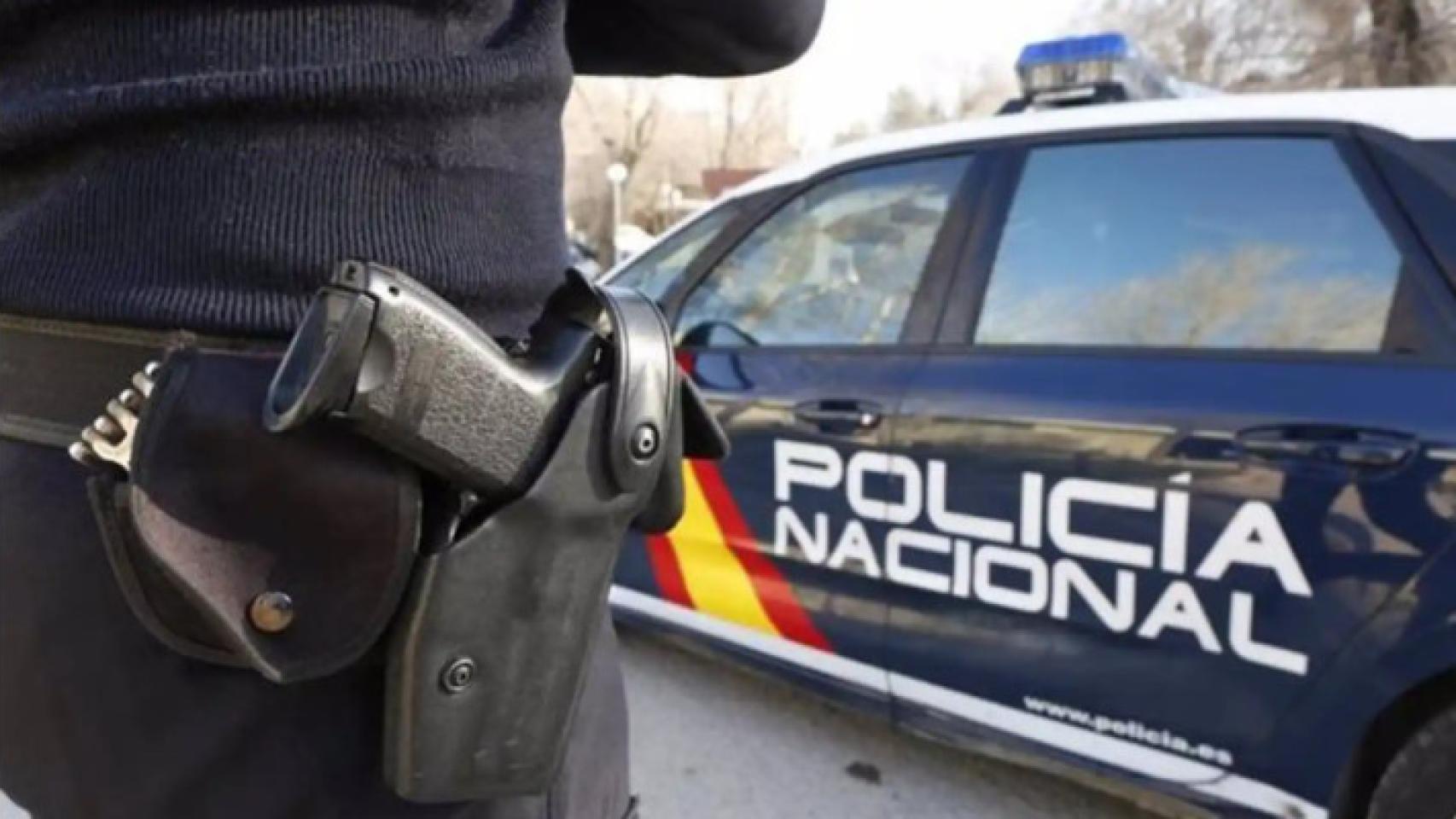 Foto de archivo de un policía nacional junto a un coche patrulla.