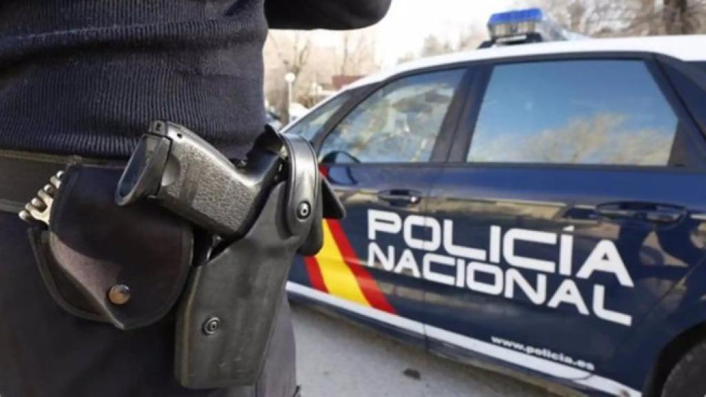 Foto de archivo de un policía nacional junto a un coche patrulla.