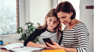 Una mujer utiliza el móvil junto a su hija (Shutterstock)