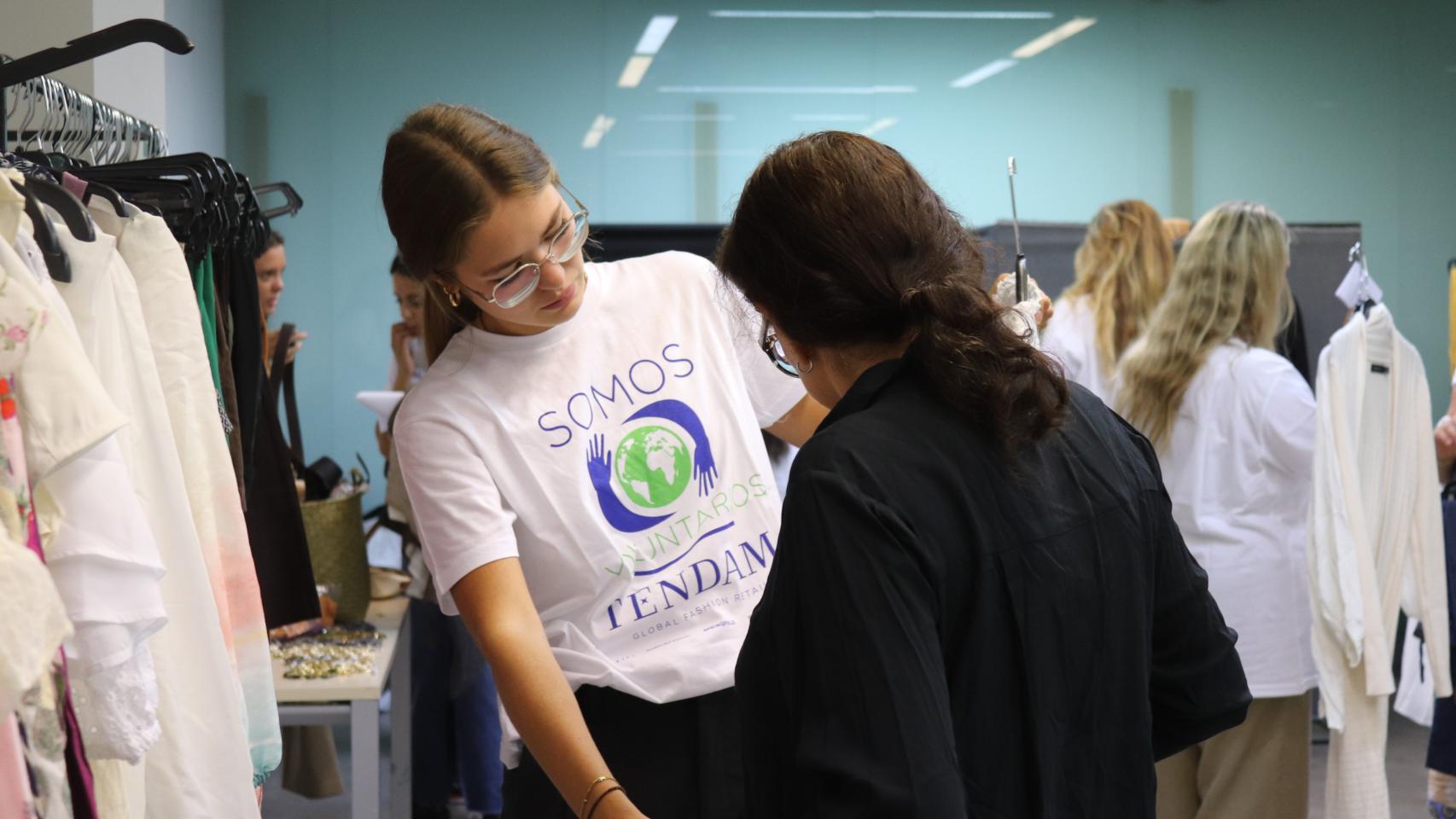 Una voluntaria de Tendam ayuda a una futura trabajadora a preparar su estilismo para la entrevista de trabajo.