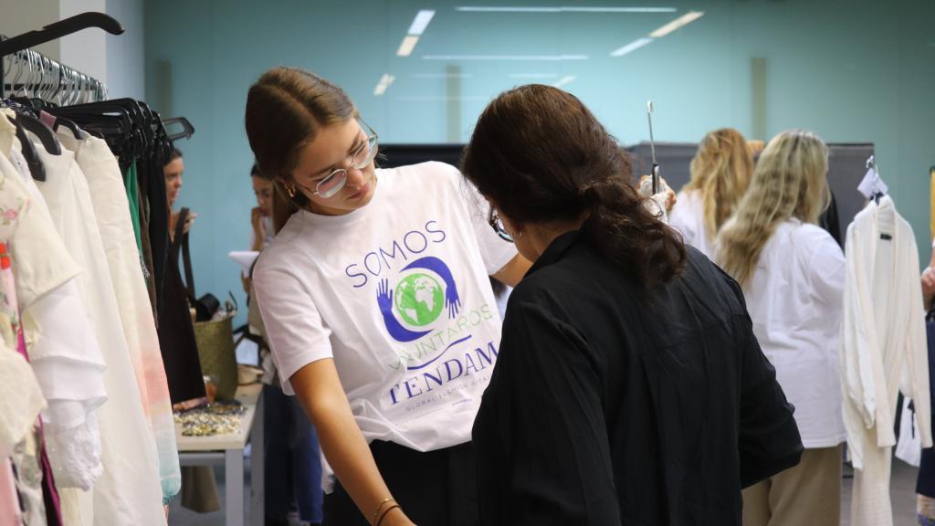 Una voluntaria de Tendam ayuda a una futura trabajadora a preparar su estilismo para la entrevista de trabajo.