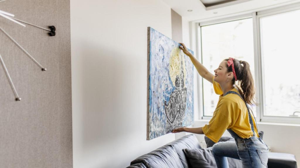 Imagen de una joven decorando el salón de su casa.