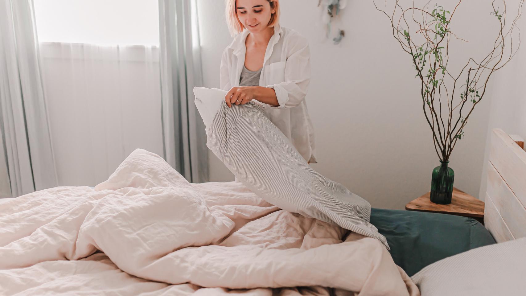 Una mujer cambia las sábanas de la cama.