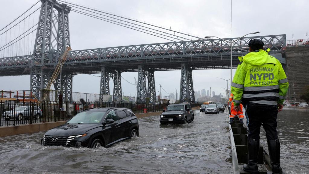 Un agente de policía de Nueva York observa cómo los coches atraviesan una calle inundada tras la tormenta tropical Ofelia.