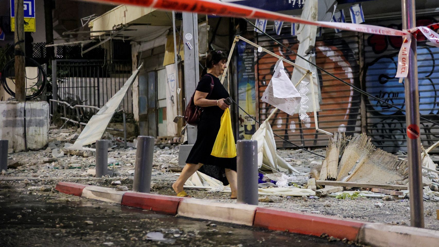 Una mujer camina entre los escombros provocados por un cohete, en Tel Aviv.