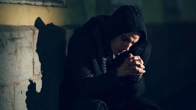 Imagen de archivo de una persona joven encapuchada y triste.
