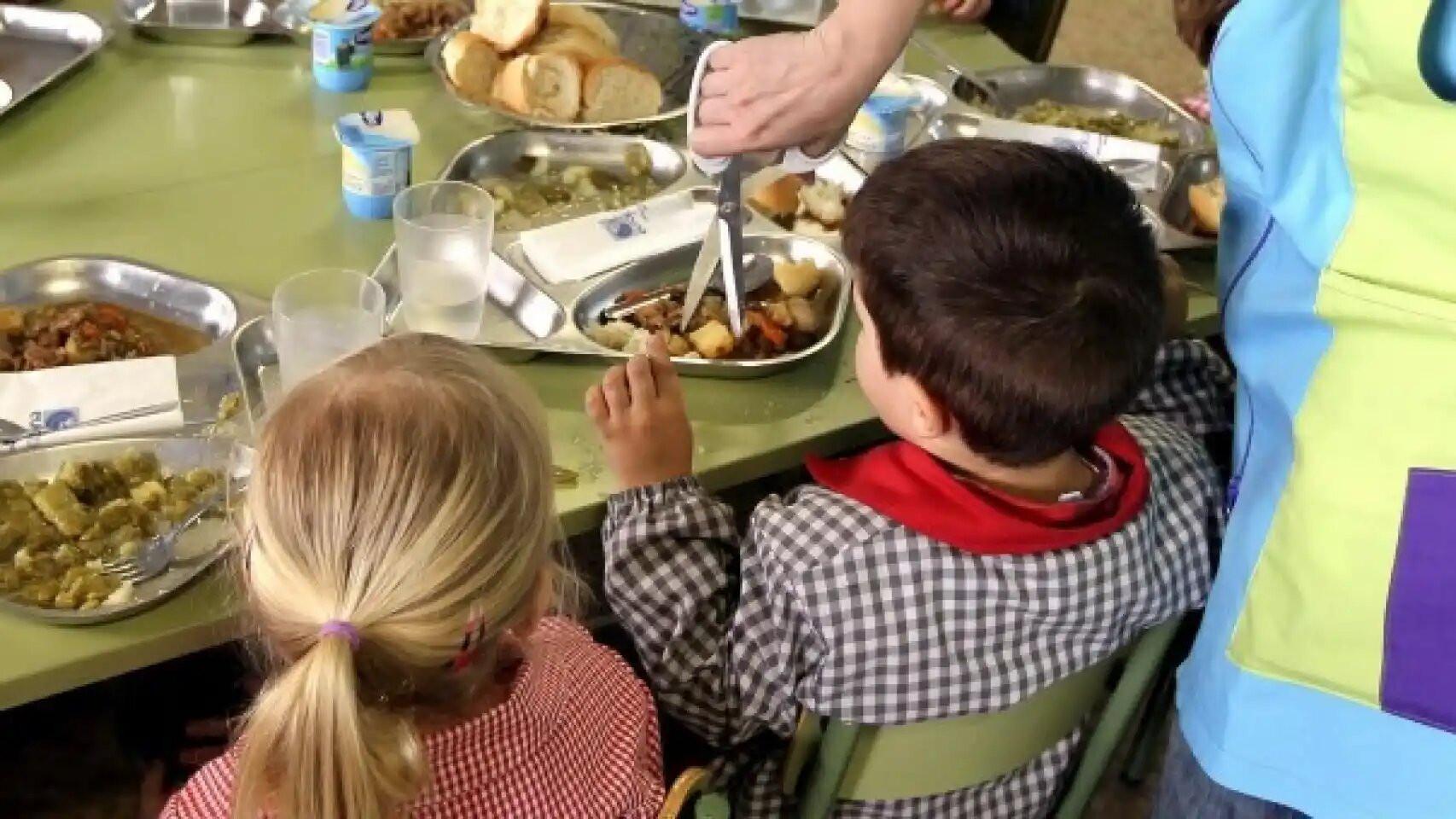 Unos niños comen en un comedor escolar.