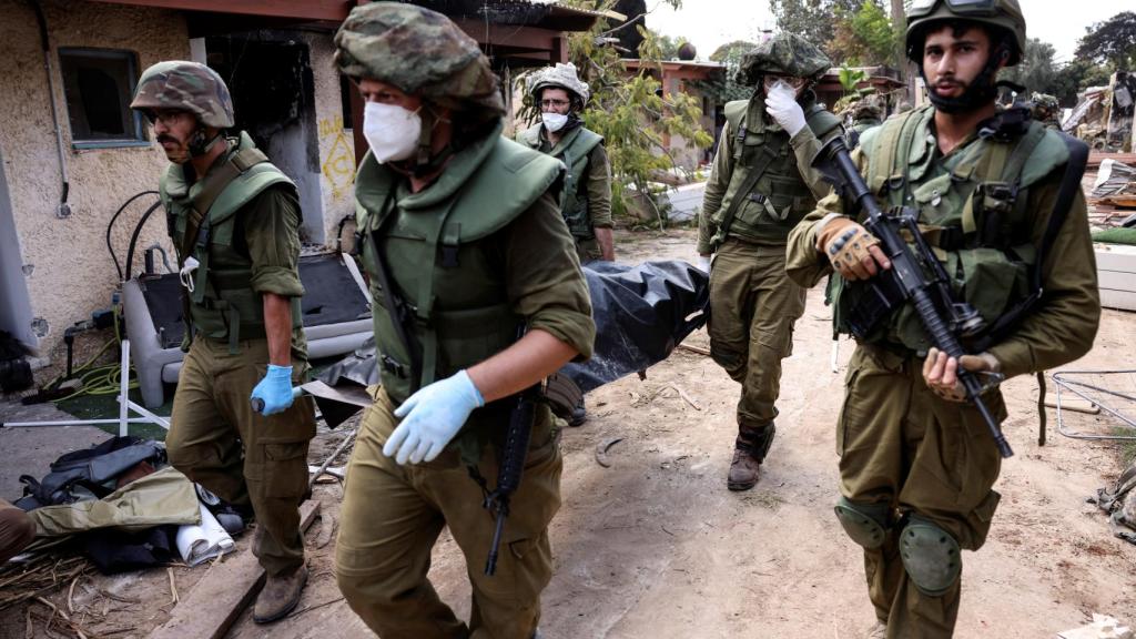 Soldados israelíes trasladan un cadáver en el kibutz de Kfar Aza.