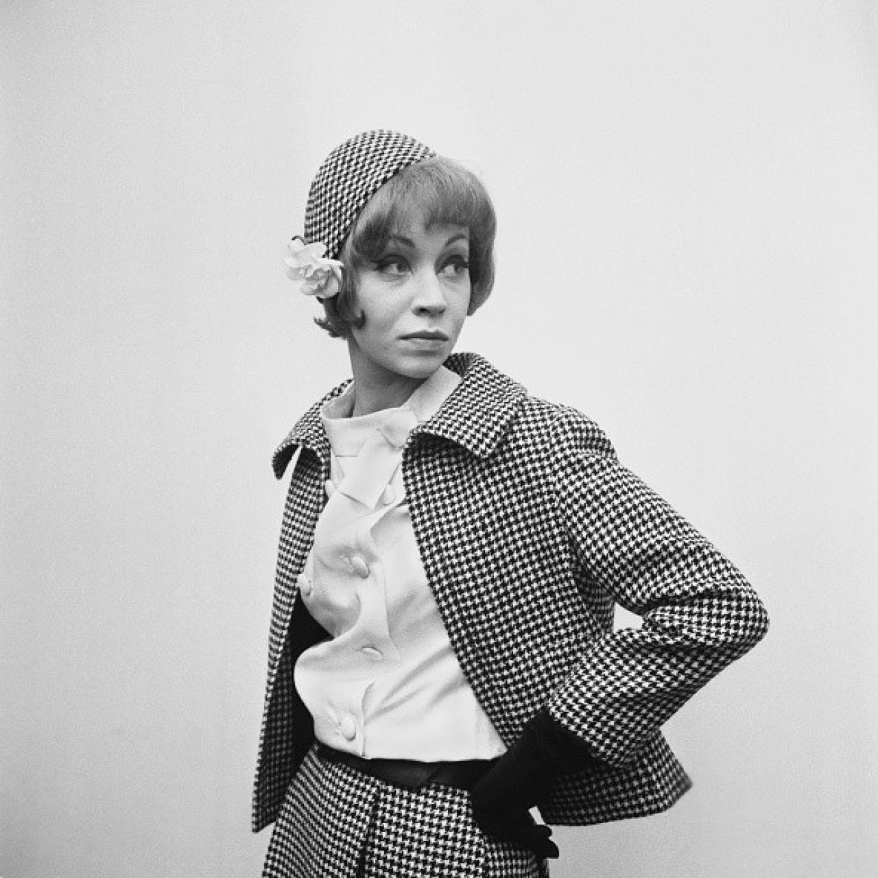 Una modelo viste un traje de pata de gallo de Christian Dior con guantes negros y un sombrero a juego en el taller de Dior, en el número 9 de Conduit Street en Mayfair, el 28 de febrero de 1962.