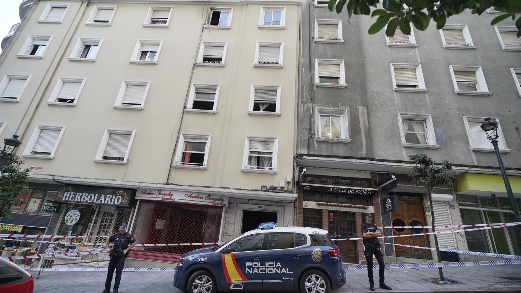 Un vehículo y dos agentes de Policía Nacional frente al edificio donde se ha producido un incendio en la calle Alfonso X el Sabio de Vigo, a 11 de octubre de 2023, en Vigo, Pontevedra, Galicia (España).