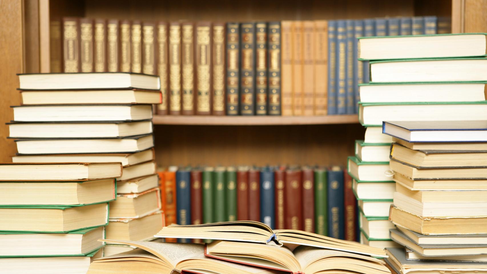Imagen de un escritorio junto a una estantería con libros.