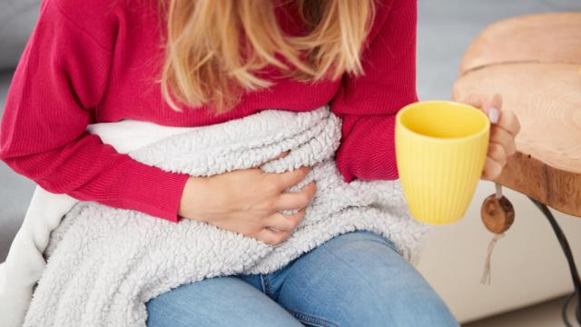 Mujer con dolores menstruales tomando té de jengibre.