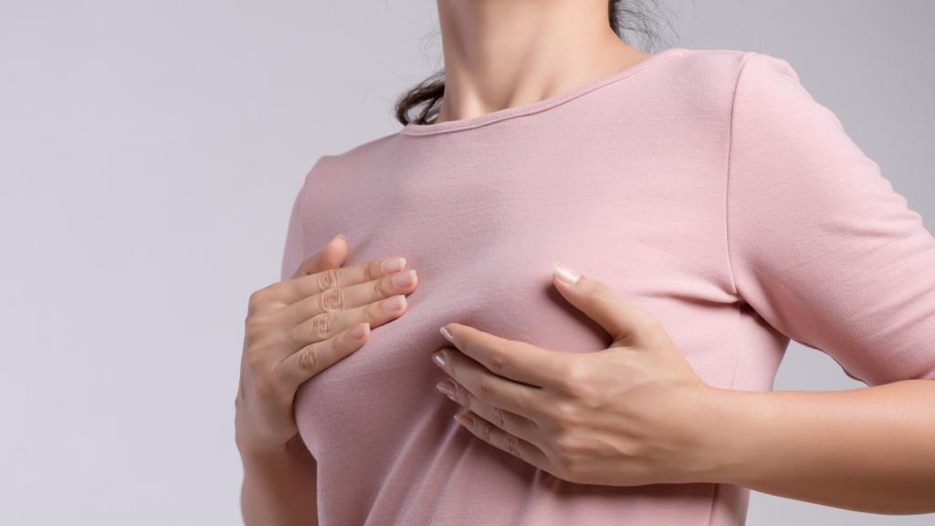 Una mujer autoexplorándose las mamas.