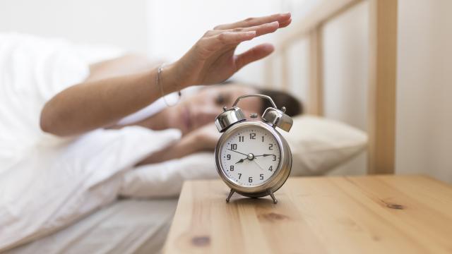 Una persona apagando un despertador.