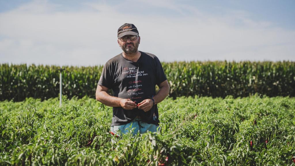 Kiko Encabo sostiene varios pimientos tiernos en una plantación.