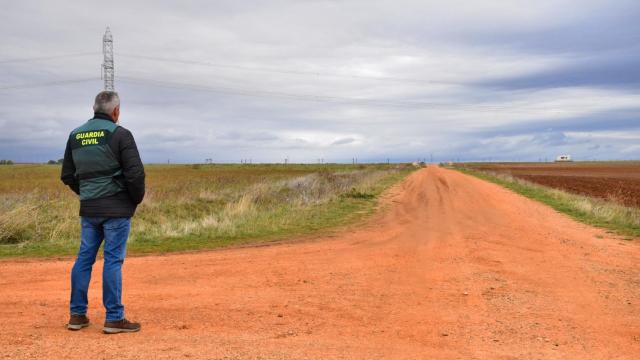 Un agente de la Guardia Civil observa el lugar donde Arancha fue atacada por cinco perros. Al fondo, la caravana del pastor, responsable de los animales