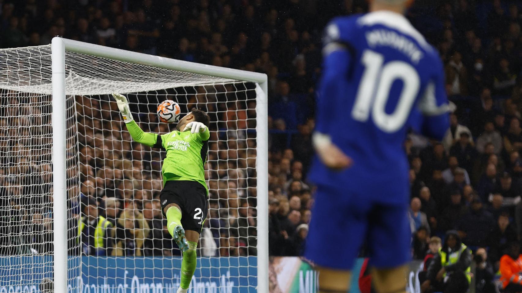 Mudryk, del Chelsea, trata de batir a Raya, el guardameta del Arsenal.