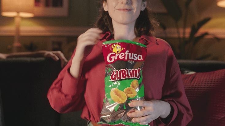 Imagen de archivo de una mujer comiendo snacks de Grefusa.