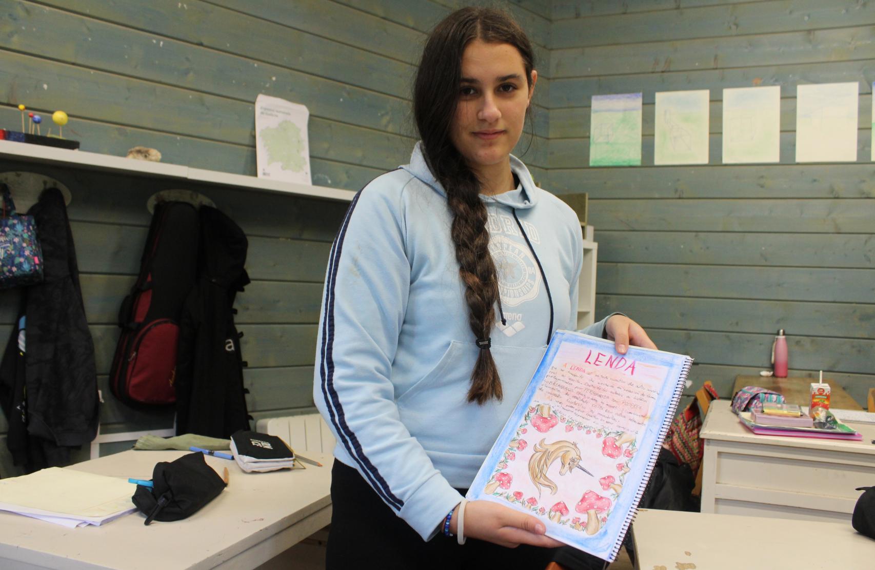 Una niña muestra su 'libro', creado por ella misma con lo aprendido.