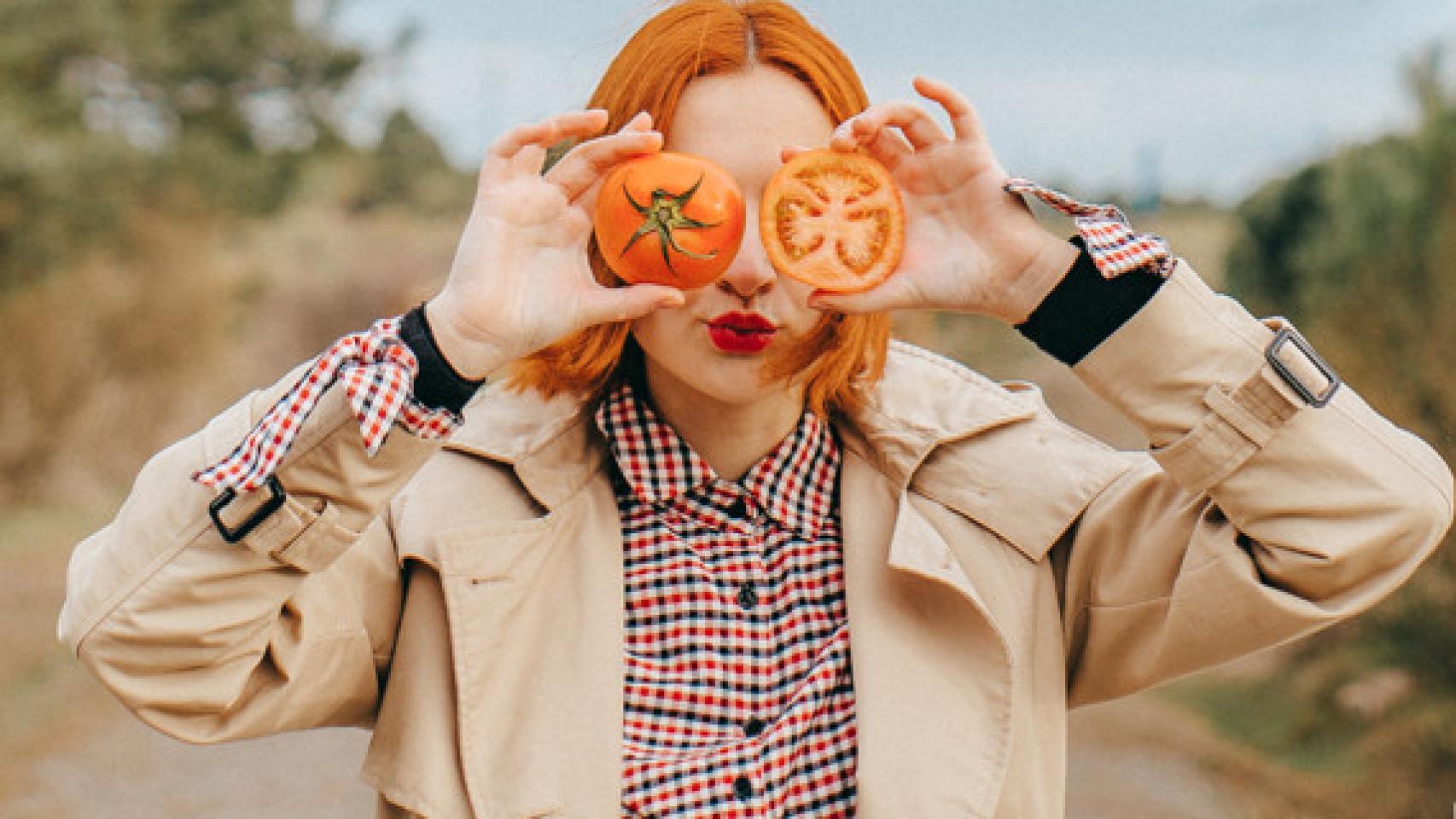 Una mujer con dos tomates promoviendo la alimentación sostenible