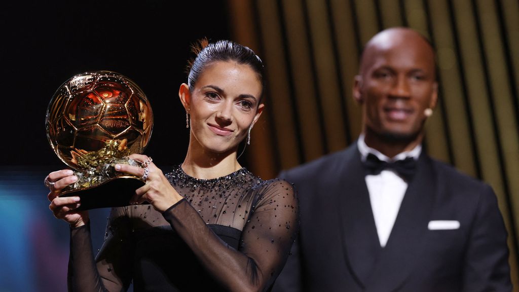 Aitana Bonmatí, con el Balón de Oro y Didier Drogba detrás.