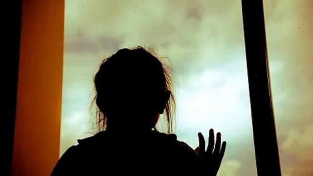 Una joven mira a través de una ventana.
