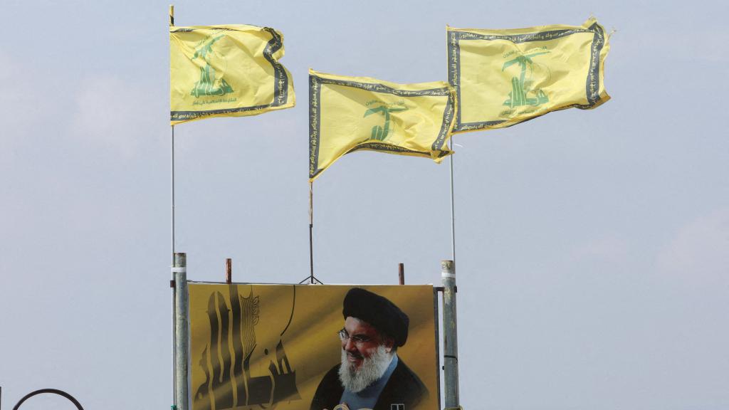 Banderas de Hezbolá ondean encima de un cartel que representa al líder del grupo terrorista.