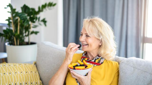 Imagen de una mujer comiendo un bol de fruta.