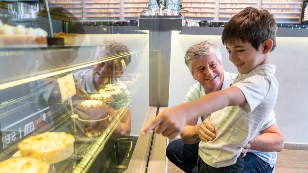Imagen de archivo de un niño con su abuelo escogiendo dulces en una pastelería.