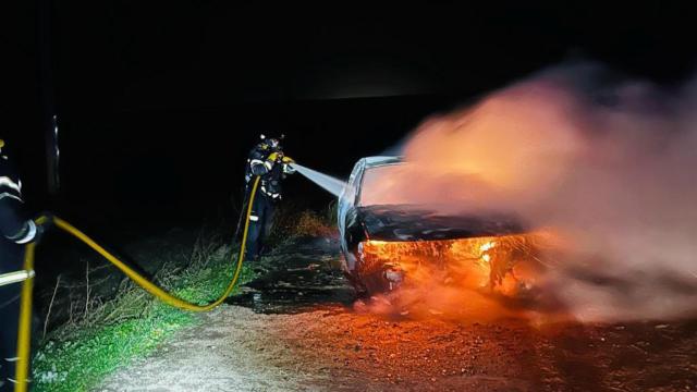 Los bomberos apagan el vehículo incendiado