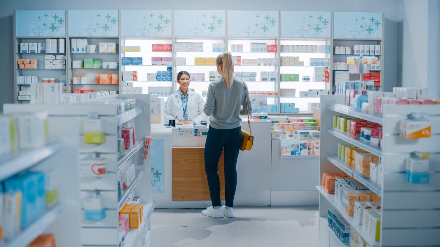 Una paciente es atendida por una farmacéutica.