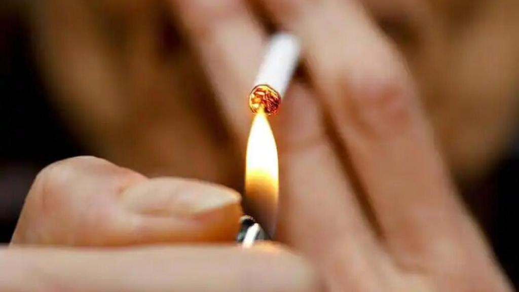 Una persona encendiéndose un cigarro.