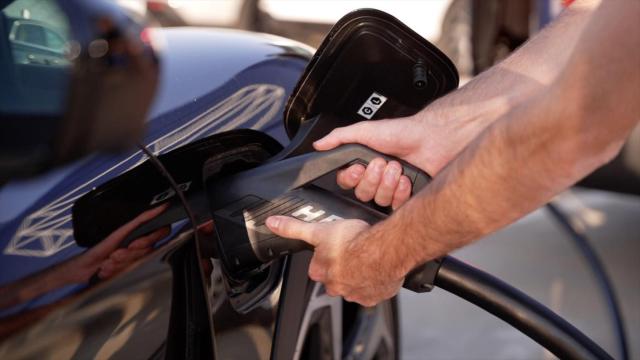 Imagen de archivo de una persona cargando un vehículo eléctrico.