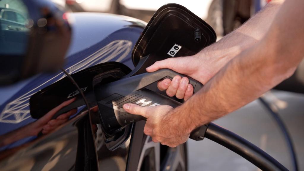 Imagen de archivo de una persona cargando un vehículo eléctrico.