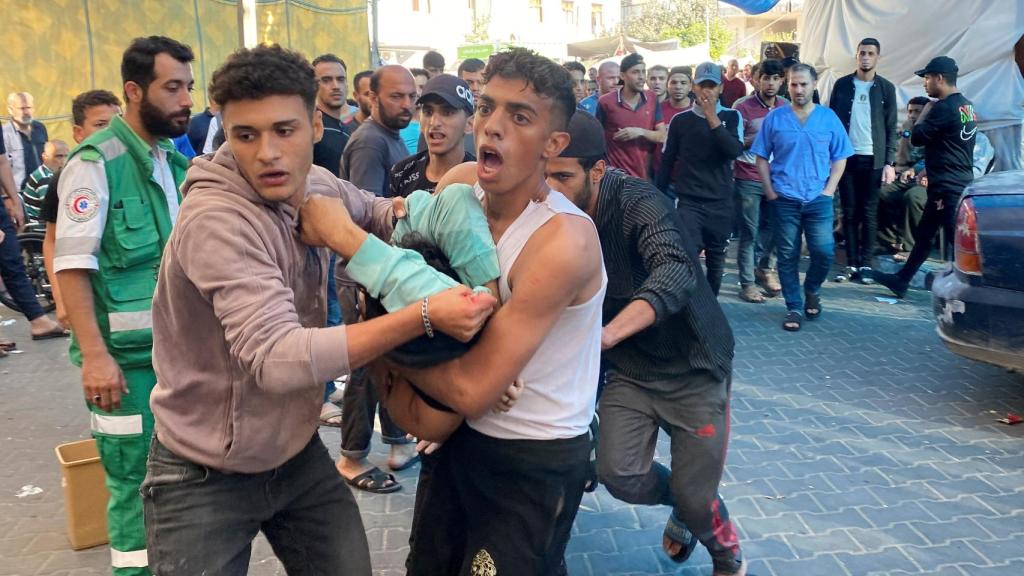 Un grupo de personas llevan a una joven herida al hospital de Al Shifa.