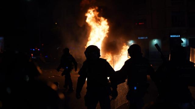 Policías en Ferraz ante un contenedor incendiado por los radicales este jueves.